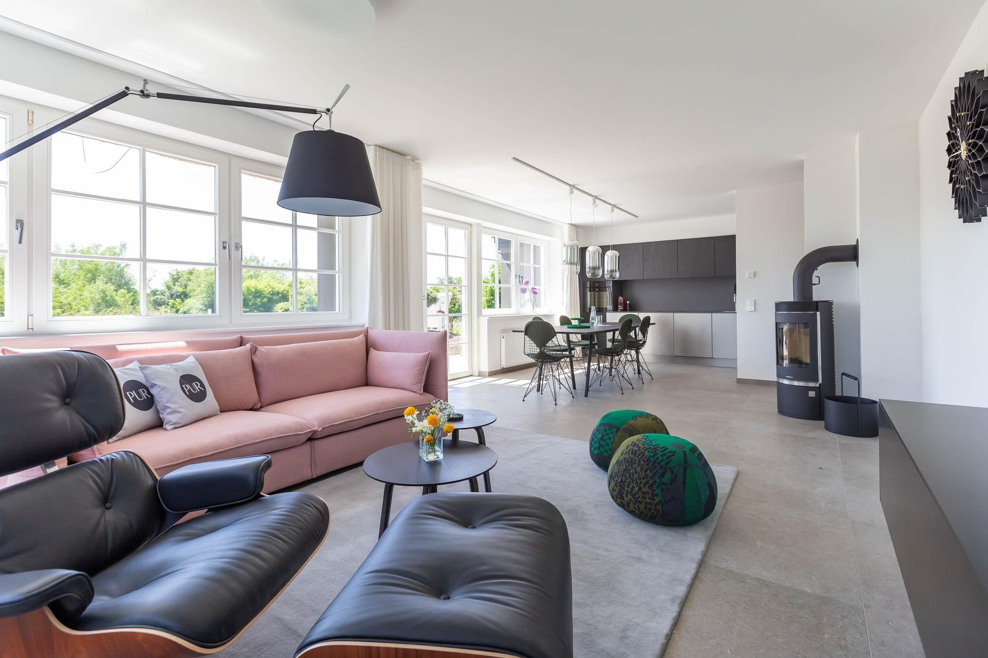 Modernes Wohnzimmer mit großen Fenstern und bequemen Möbeln.