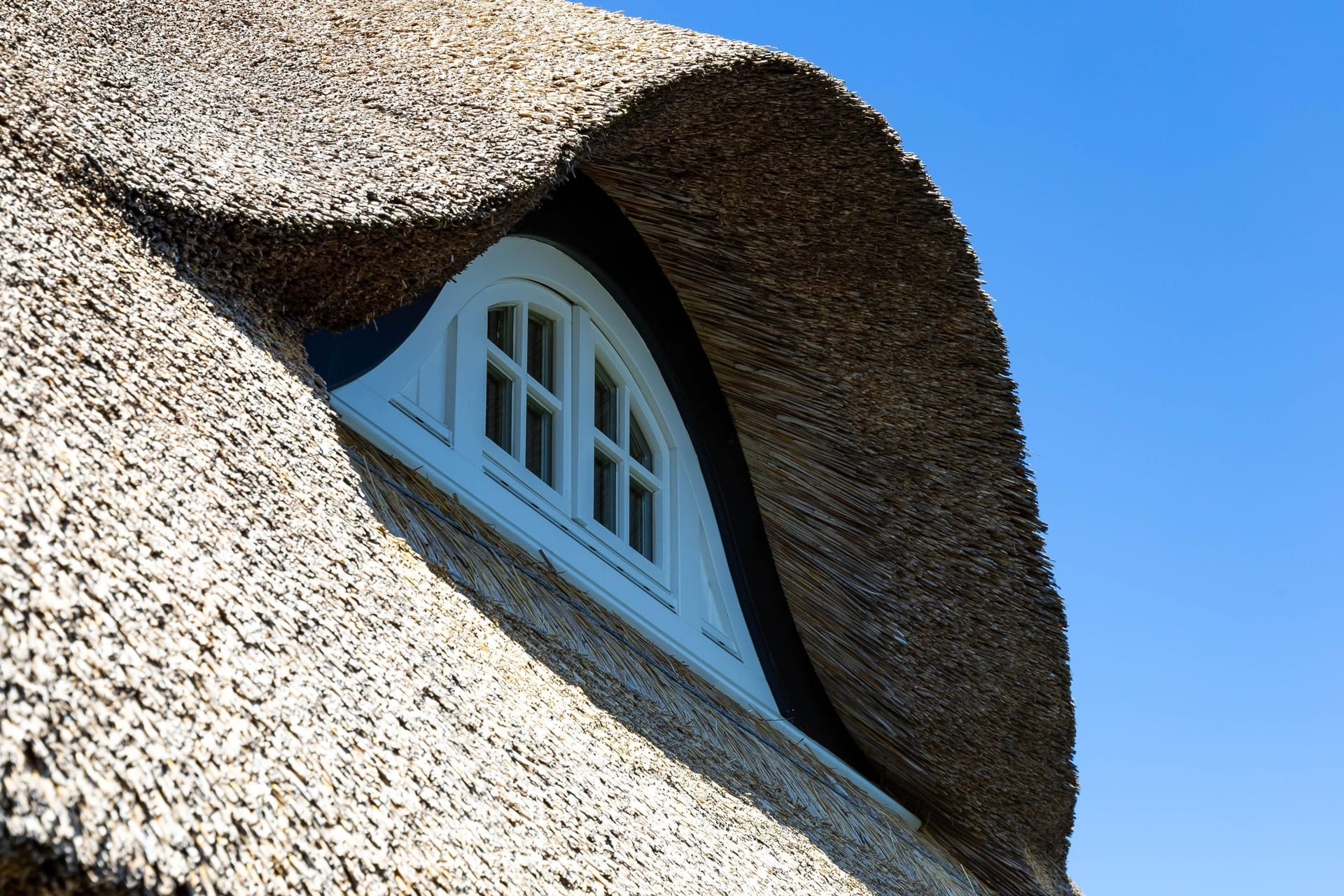 Außenansicht eines Reetdachs mit Fenster