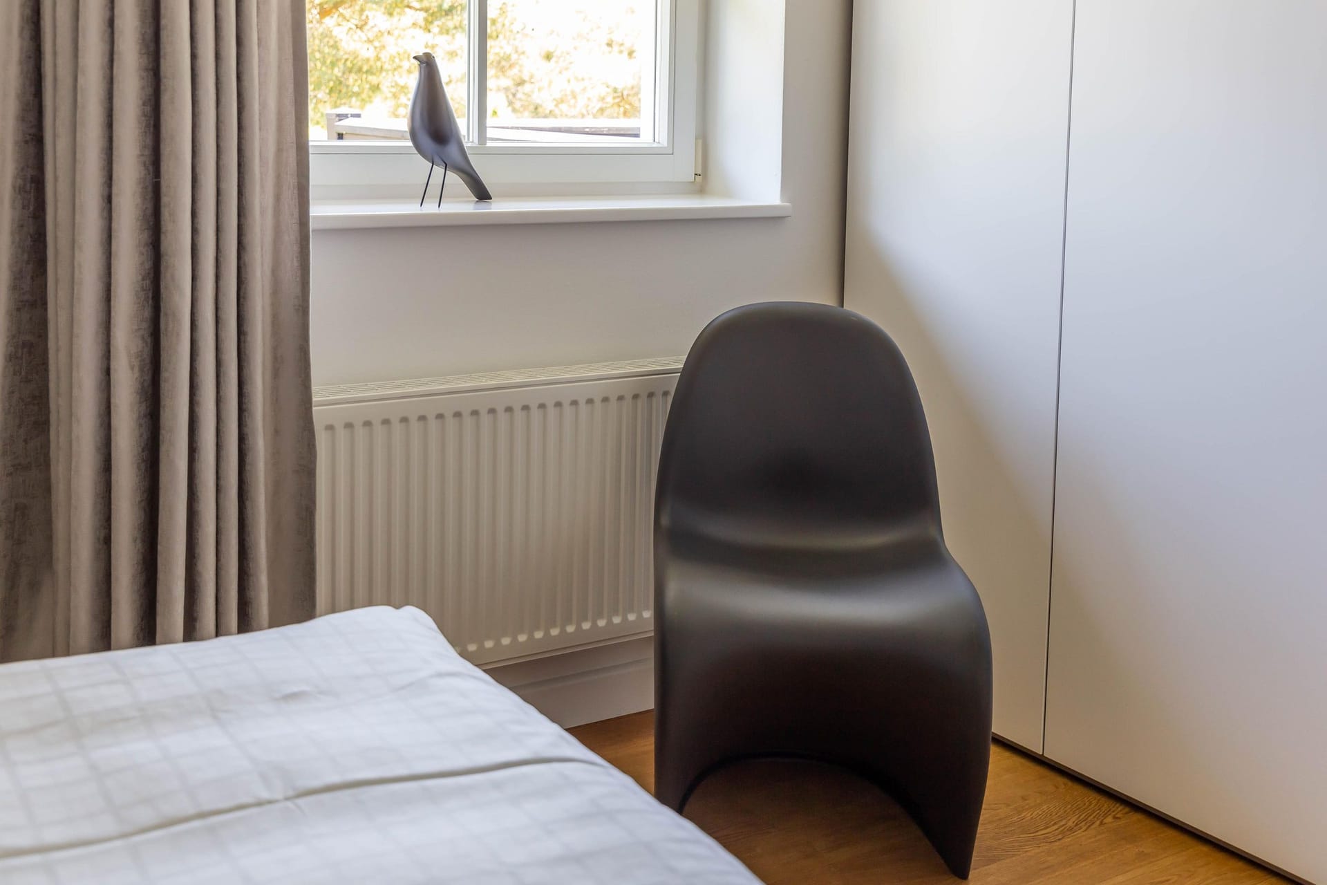Schlafzimmer mit Bett und schwarzem Stuhl