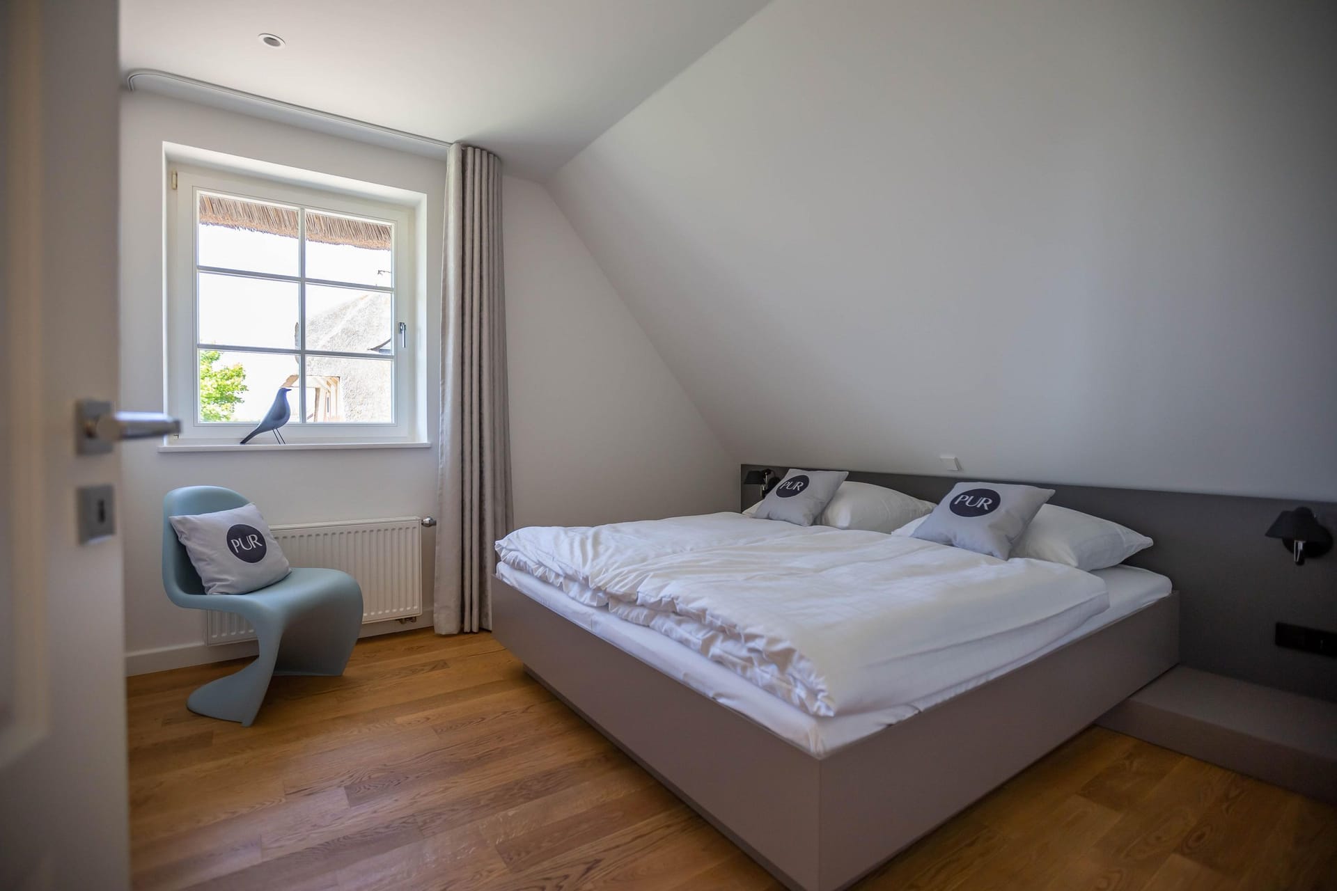 Helles Schlafzimmer mit Doppelbett und Stuhl