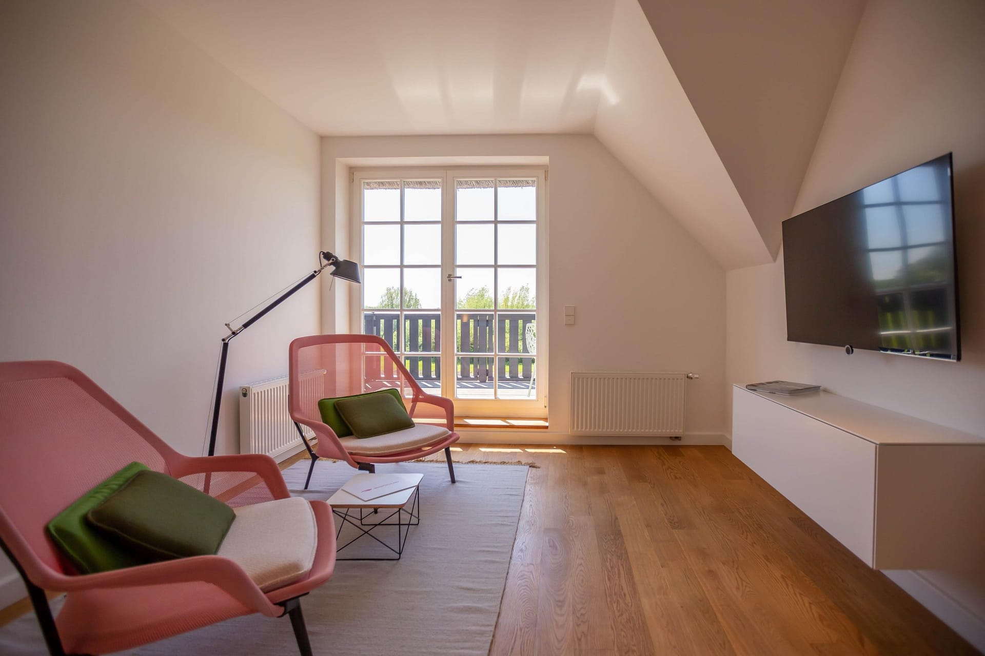 Helles Wohnzimmer mit pinken Sesseln und TV