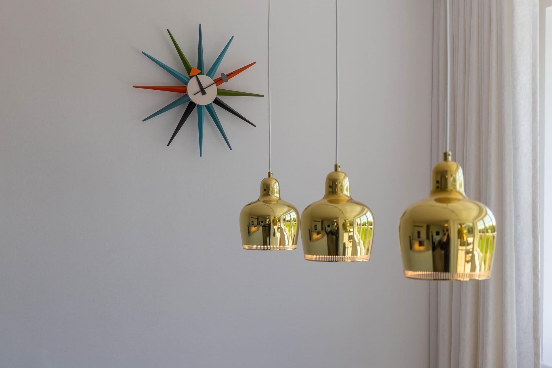 Wohnzimmer mit goldenen Lampen und bunter Uhr