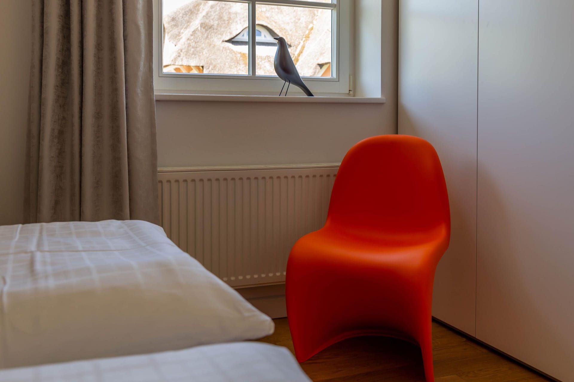 Schlafzimmer mit orangefarbenem Stuhl und Fenster