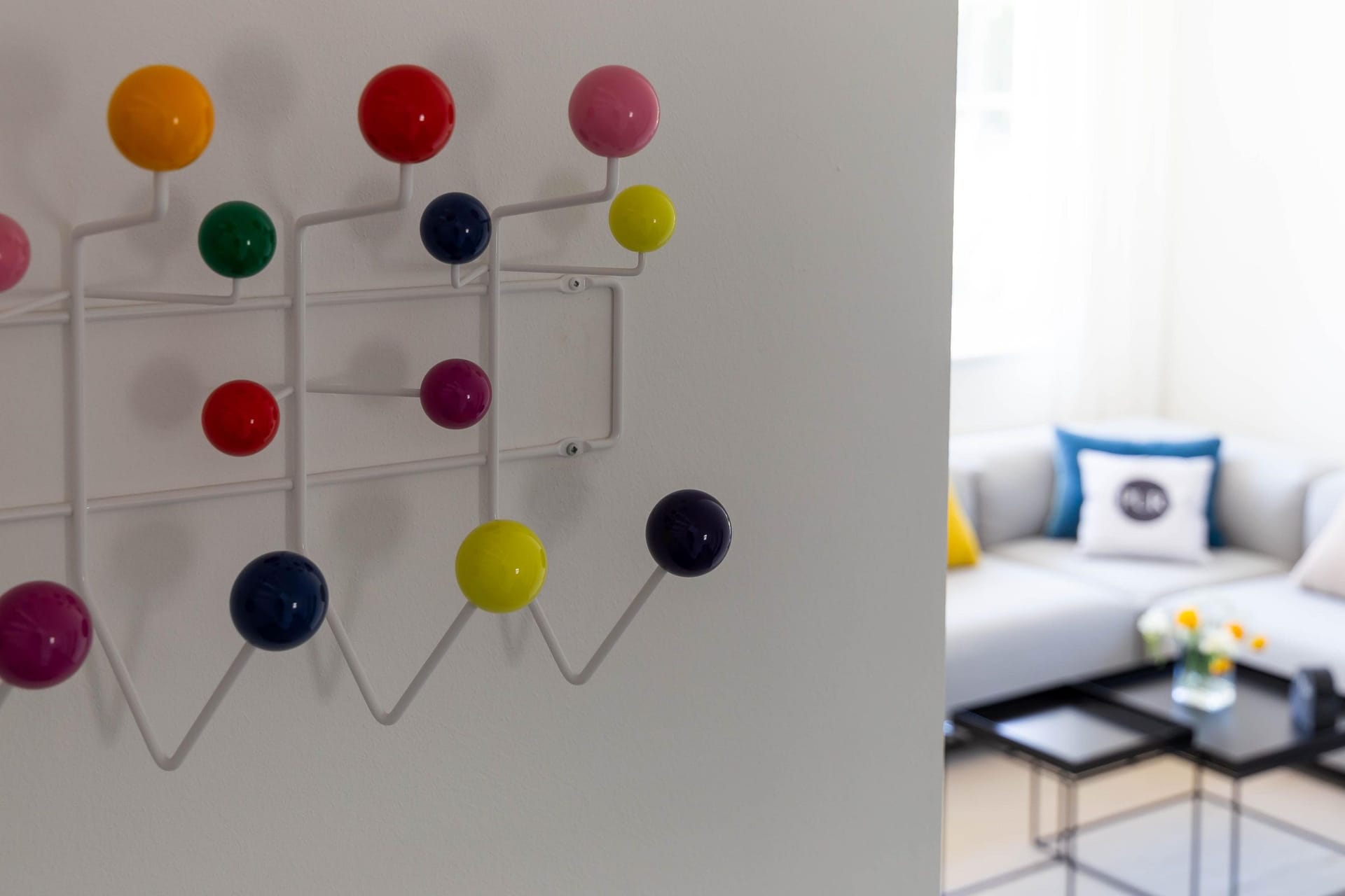 Helles Wohnzimmer mit grauem Sofa und buntem Garderobenhaken