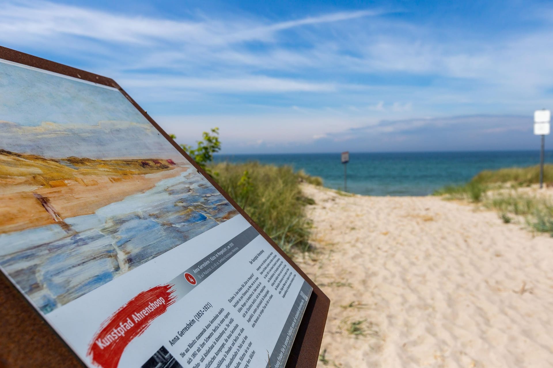 Strand mit Informationsschild und Blick aufs Meer