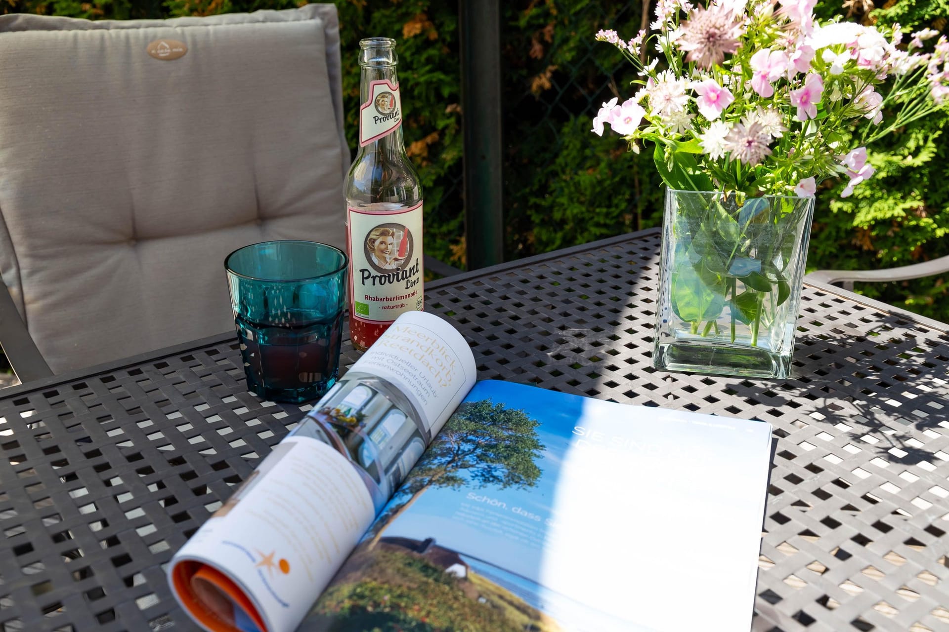 Terrasse mit Tisch, Getränk und Blumen