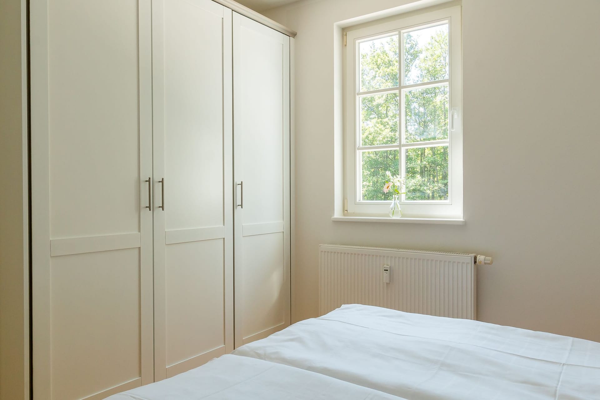 Schlafzimmer mit hellem Fenster und Schrank