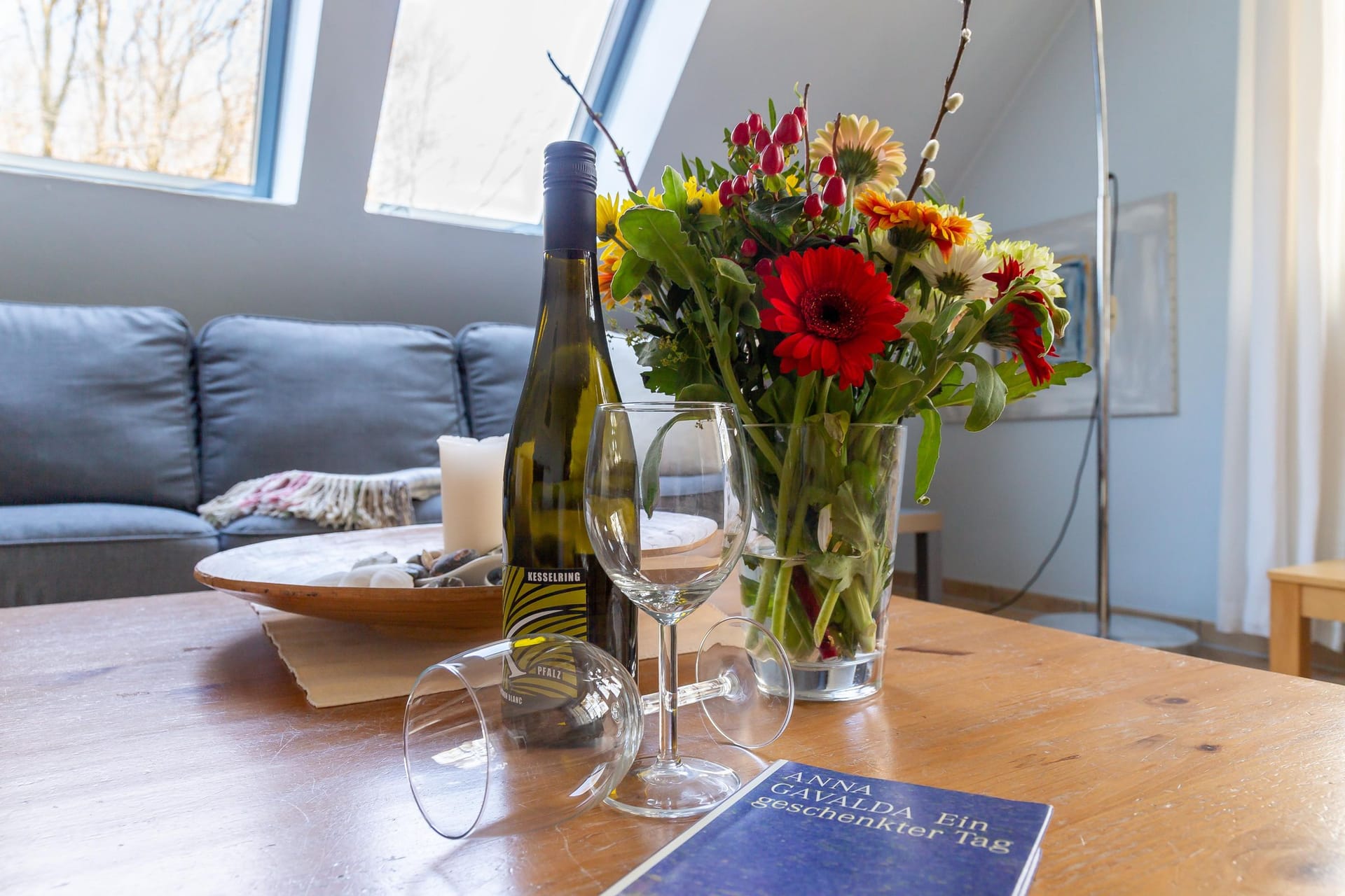 Wohnzimmer mit blåem Sofa und Wein