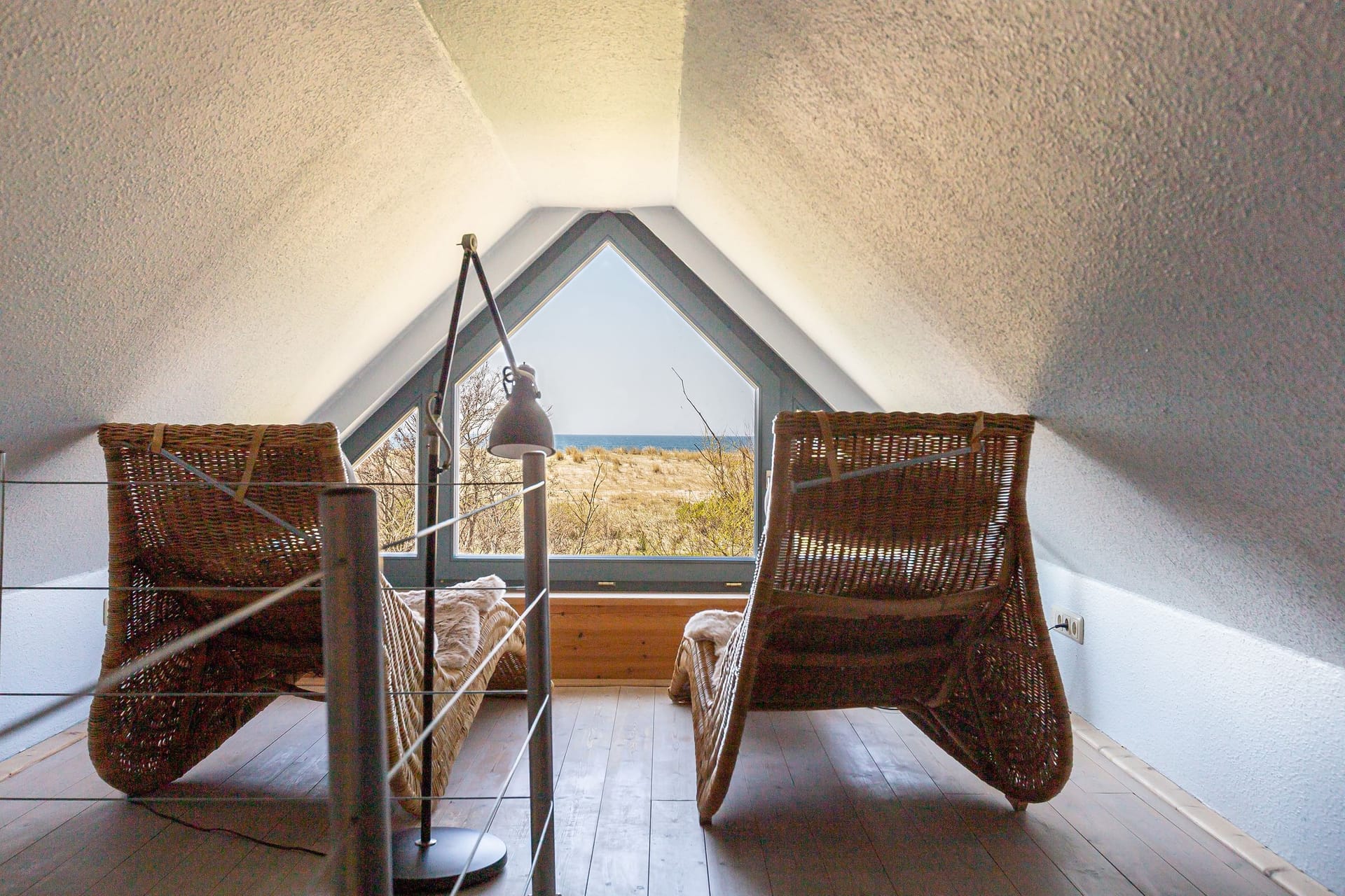 Wohnbereich mit Rattanstühlen und Dünenblick