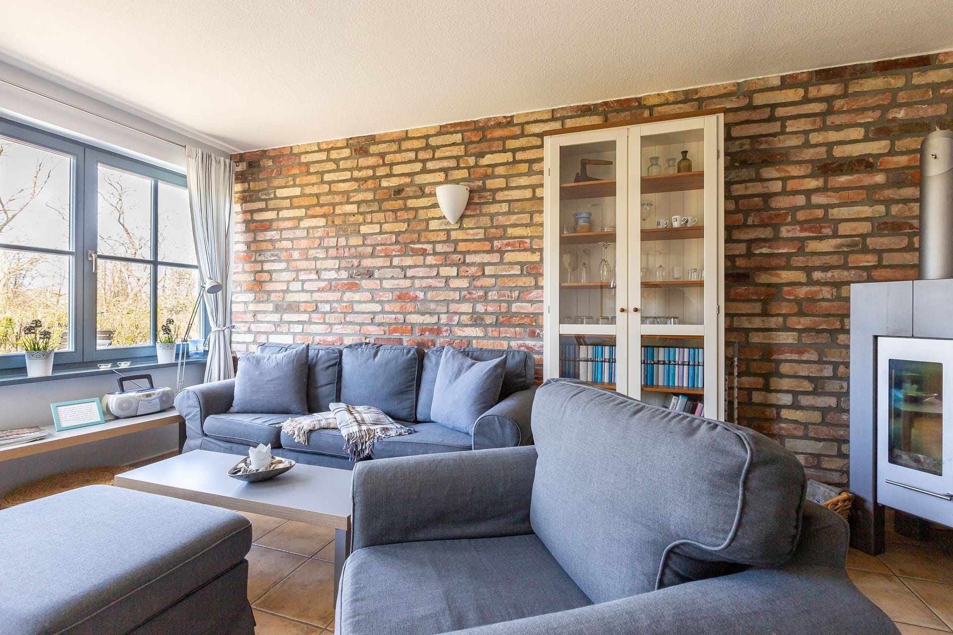 Geräumiges Wohnzimmer mit grauen Sofas und Kamin