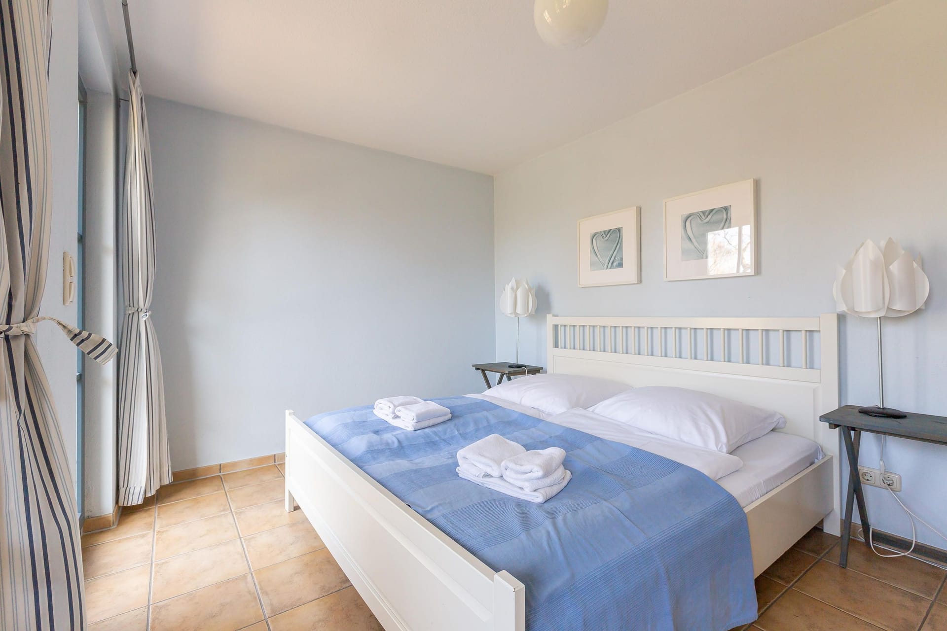 Helles Schlafzimmer mit Doppelbett und Kunstwerken