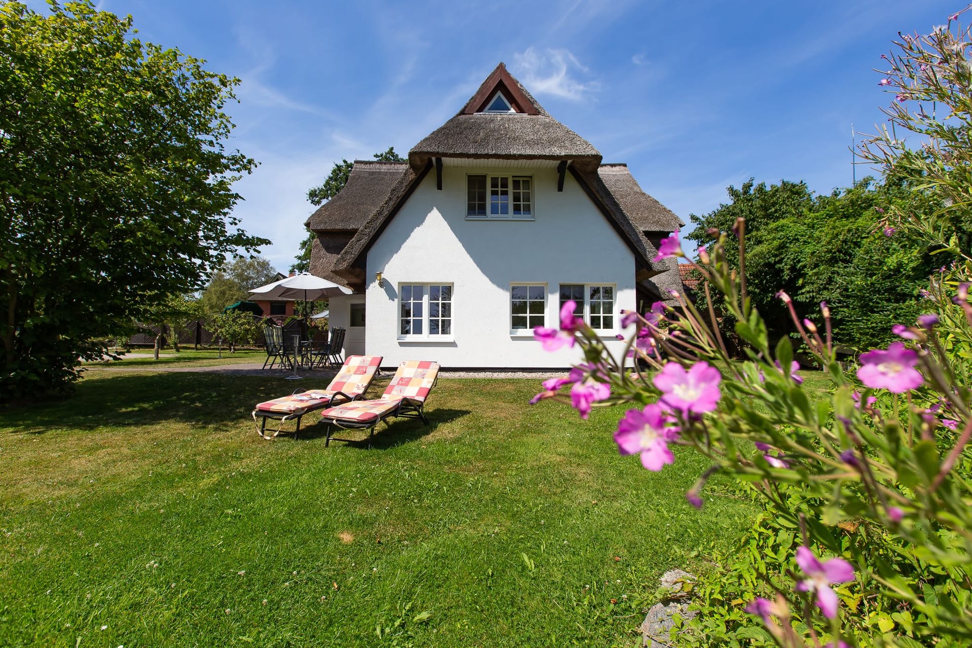 Außenansicht eines Ferienhauses mit Garten und Sonnenterrasse.