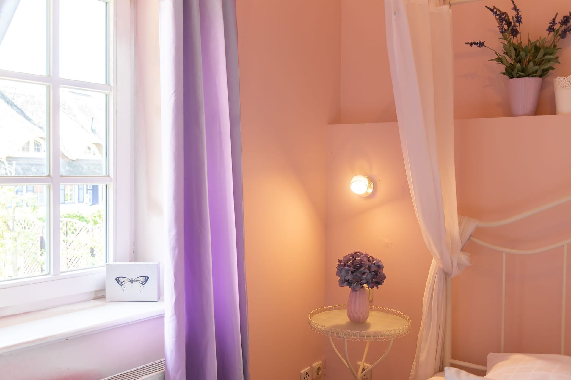 Schlafzimmer mit hellem Bett und lila Vorhängen