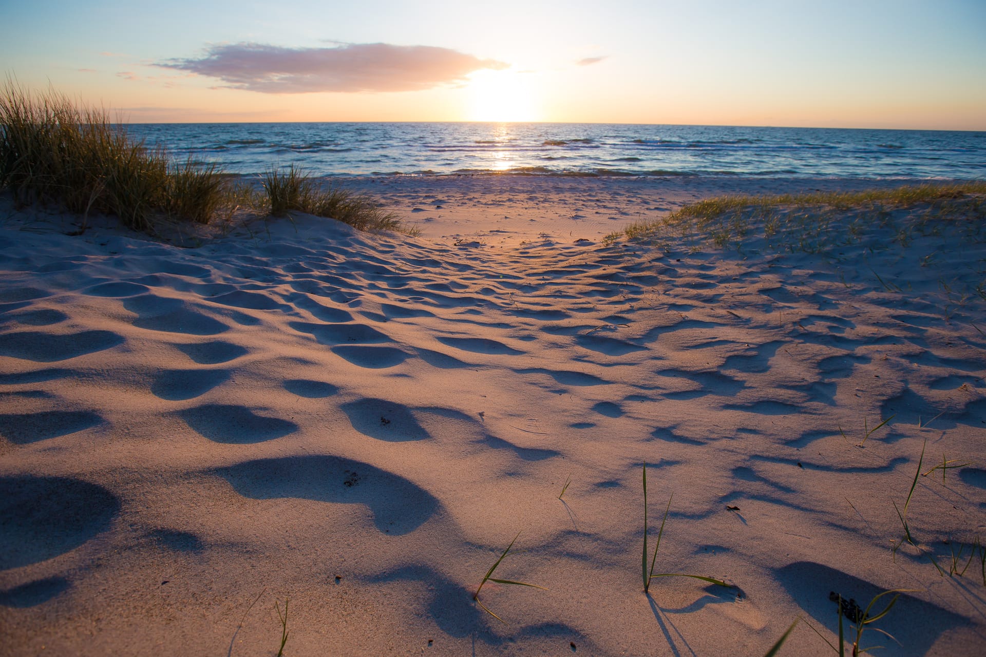 Ein sandiger Weg zum Strand mit Blick auf das Meer.
