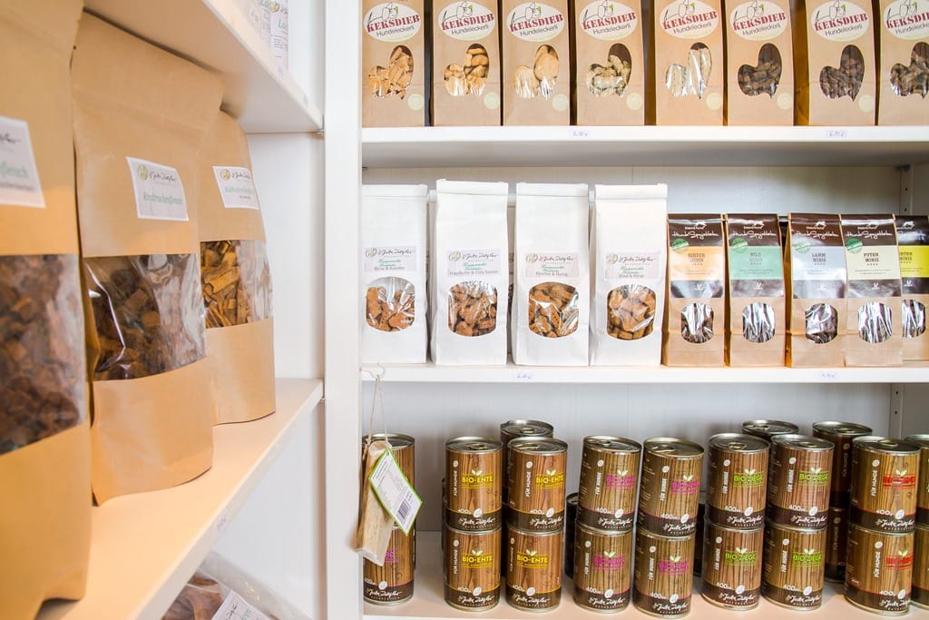 In einem Hundeladen sind Regale mit verschiedenen Hundekeksen und Dosen mit Hundefutter ausgestellt.