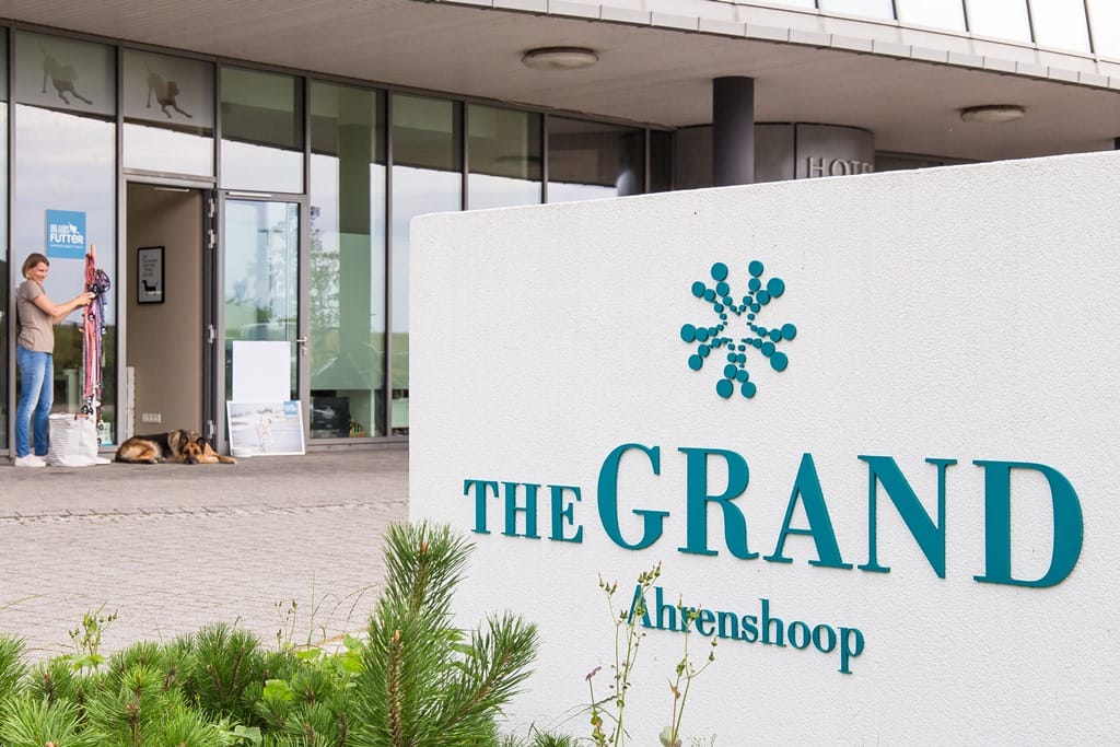 Der Eingangsbereich des Hotels The Grand Ahrenshoop beherbergt auch den separaten Hundeladen Urlaubsfutter, dessen Logo an der Glastür sichtbar ist.