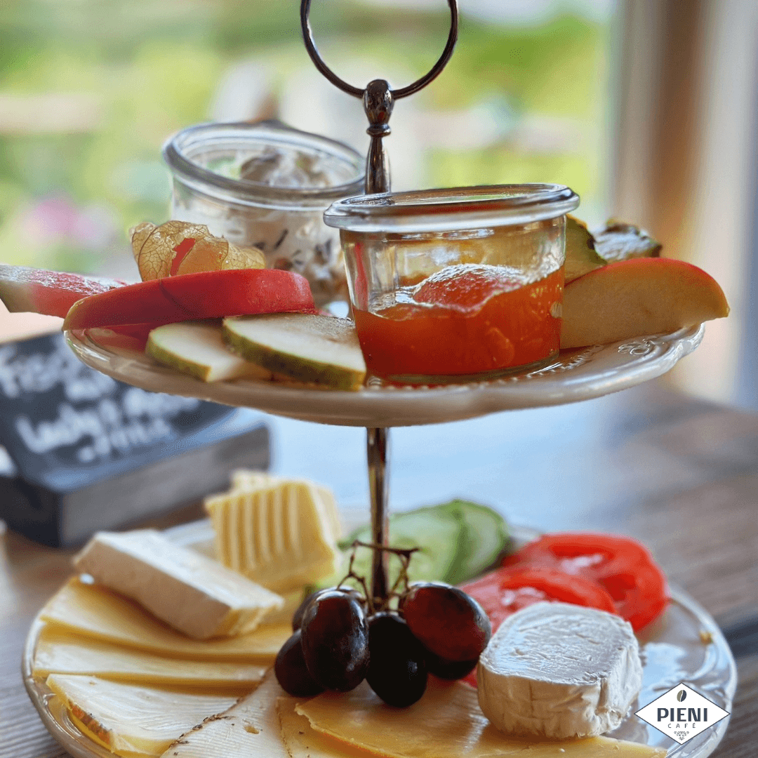 Frühstückstablett mit Käse, Obst, Honig und Getränken.