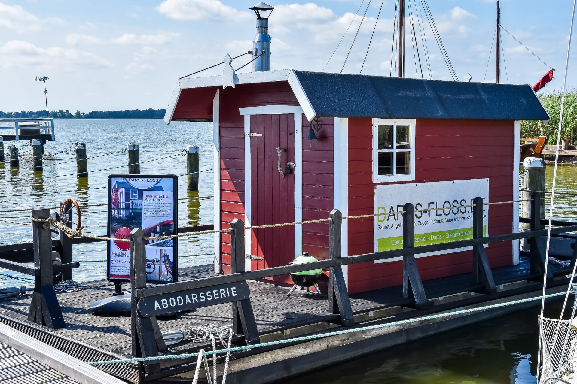 Ein rotes Saunafloß an einer Anlegestelle im Hafen eines Ostseebereichs.