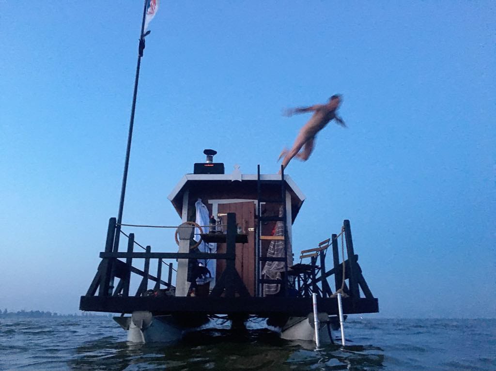 Ein Floß auf dem Wasser, ein Mensch springt hinein.