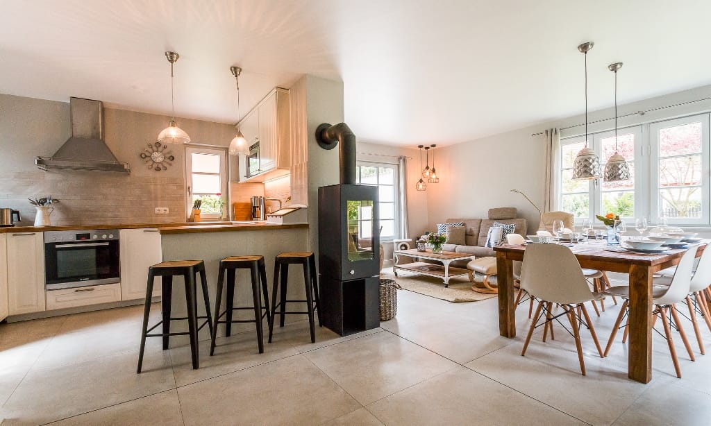 Eine moderne Ferienwohnung in Dierhagen kombiniert eine offene Küche mit einem Ess- und Wohnbereich und einem Kaminofen.