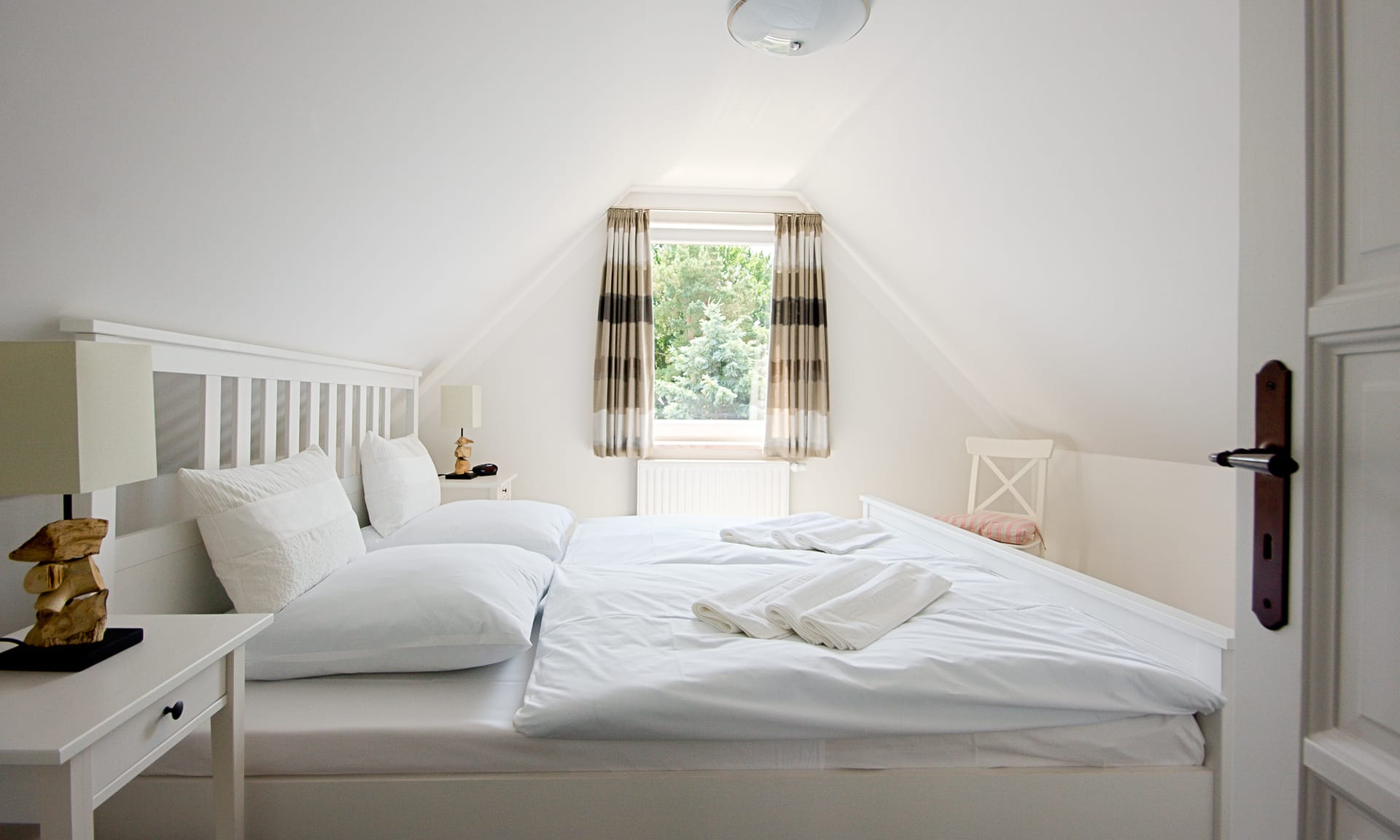 Schlafzimmer mit Doppelbett, Nachttischen mit Lampen und einem Fenster.