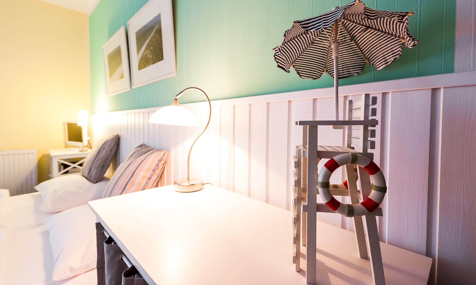 Schlafzimmer mit Holzpaneelwand, Tischlampe und maritimer Dekoration.