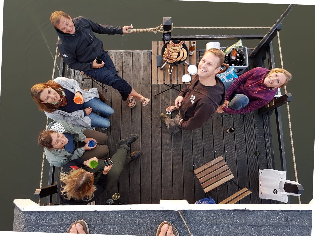 Gruppe von Menschen auf dem Floß, sie haben Getränke und grillen.