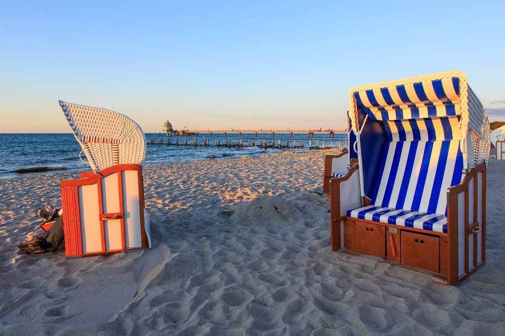 Zwei Strandkörbe am Strand bei Sonnenuntergang.