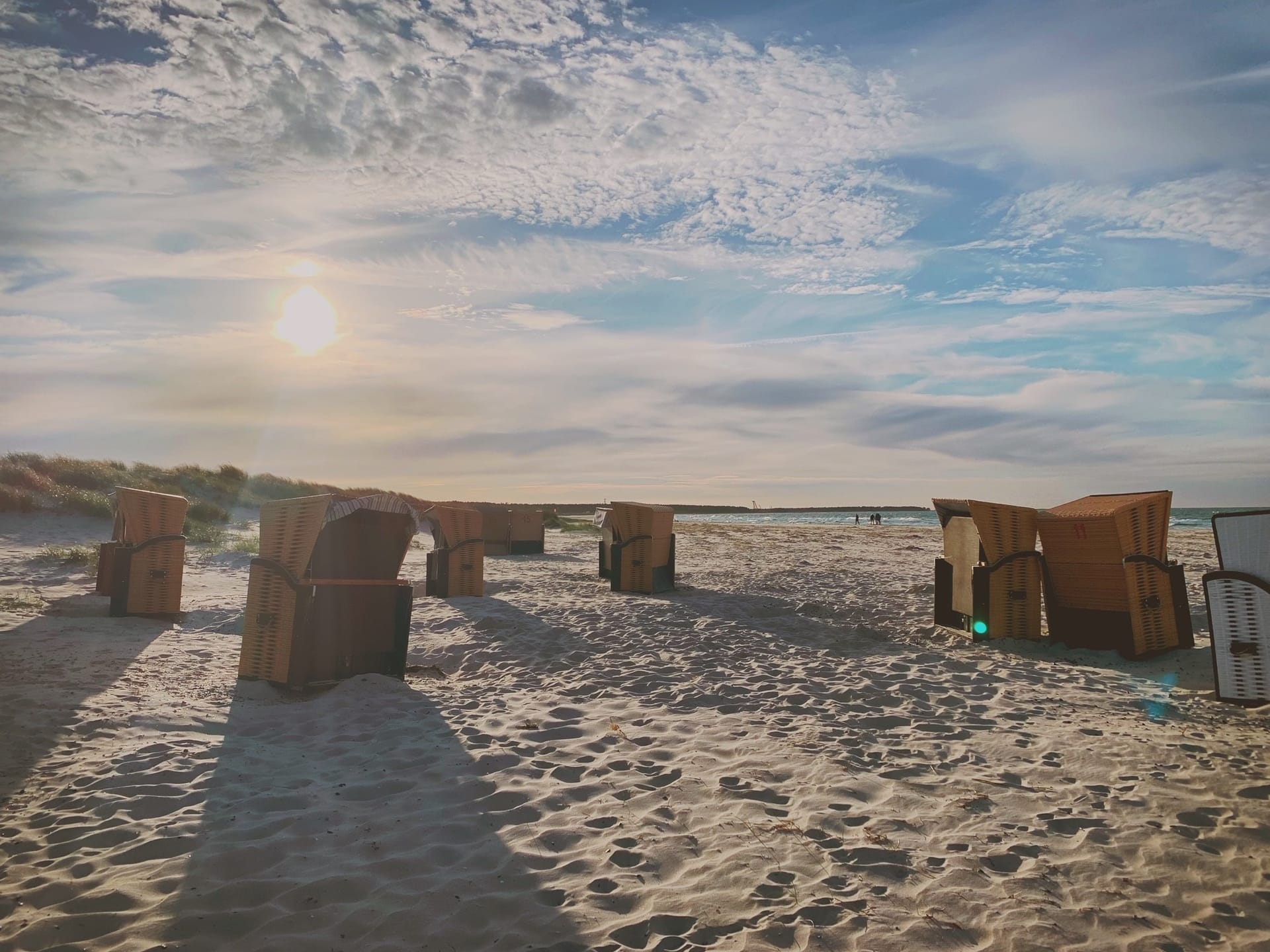 Blick auf den Strand mit Strandkörben, die Sonne scheint.