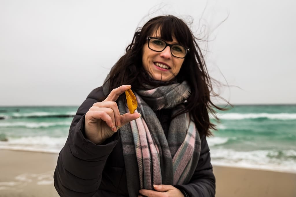 Eine Frau hält an einem windigen Strand Bernstein.