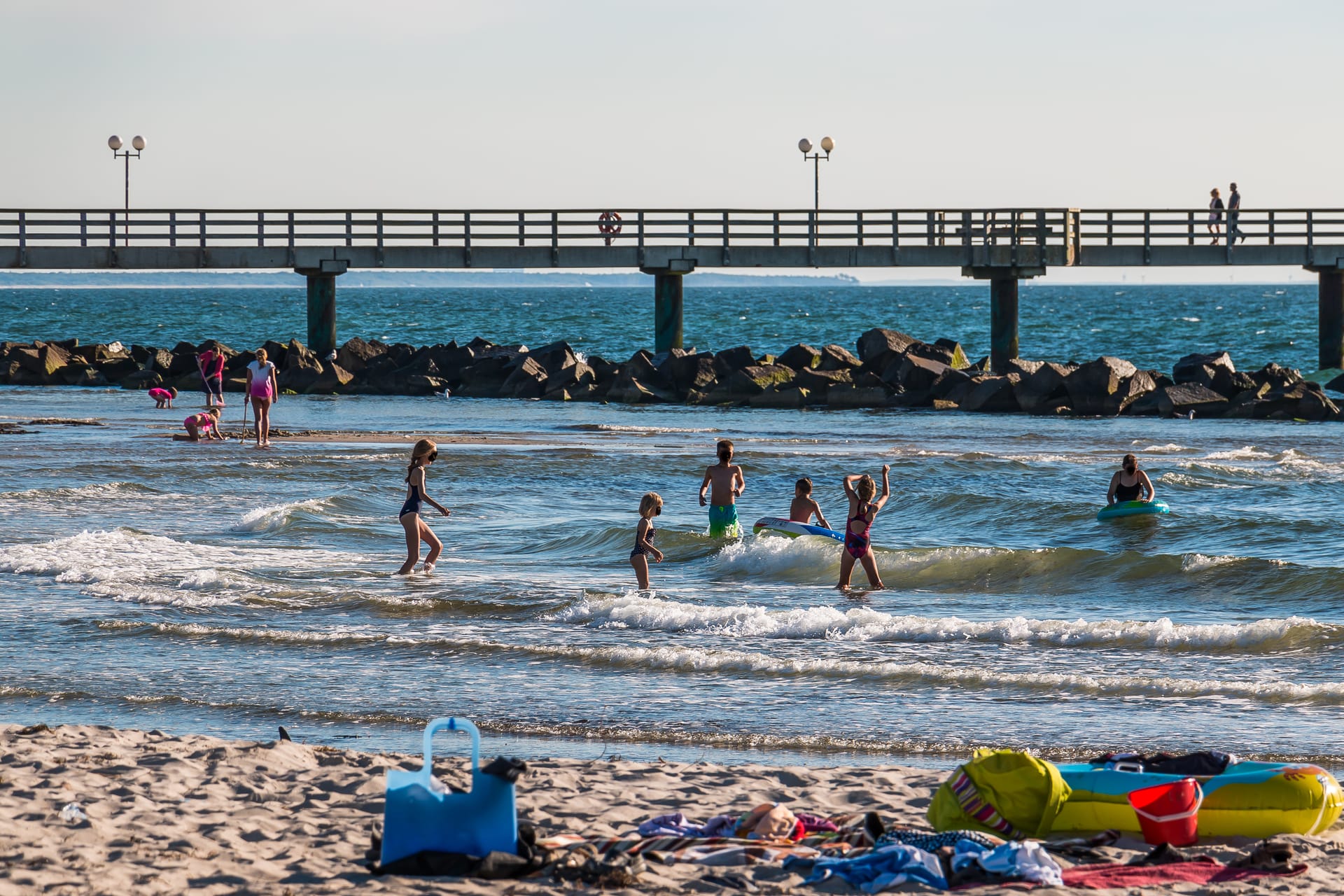 Kinder spielen im flachen Ostseewasser vor der Seebrücke