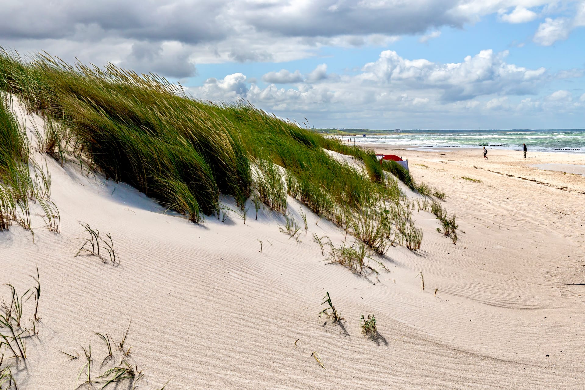 Düne mit Strandgras am Ostseestrand unter wolkigem Himmel
