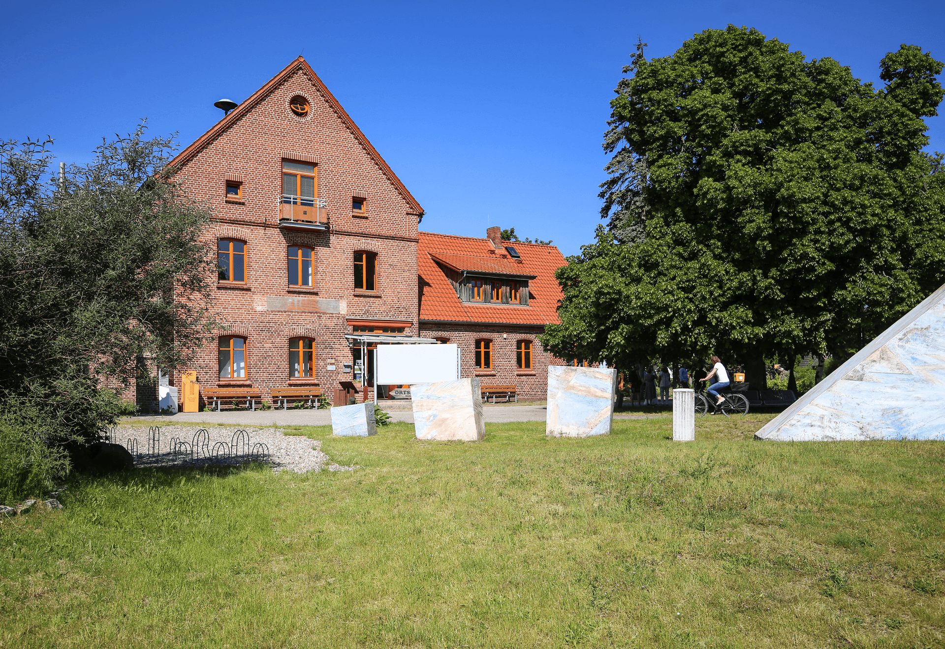 Historisches Backsteingebäude mit Kunstobjekten im Grünen
