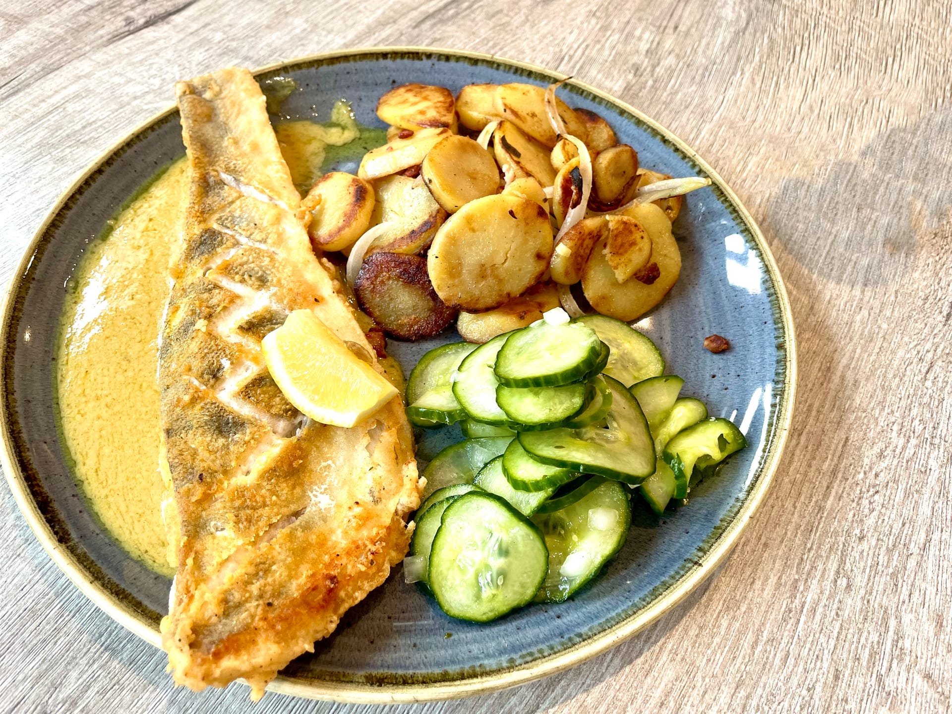 Gebratener Fisch mit Bratkartoffeln und Gurkensalat