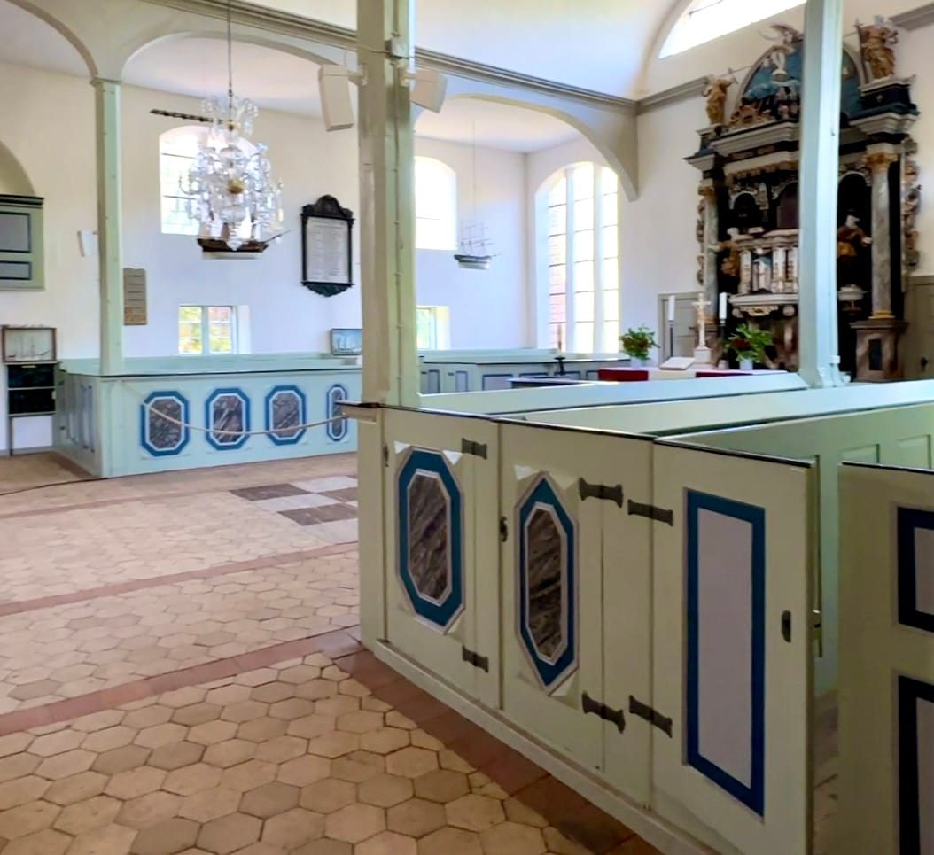 Heller Kircheninnenraum mit Emporen, Kronleuchter und Altar