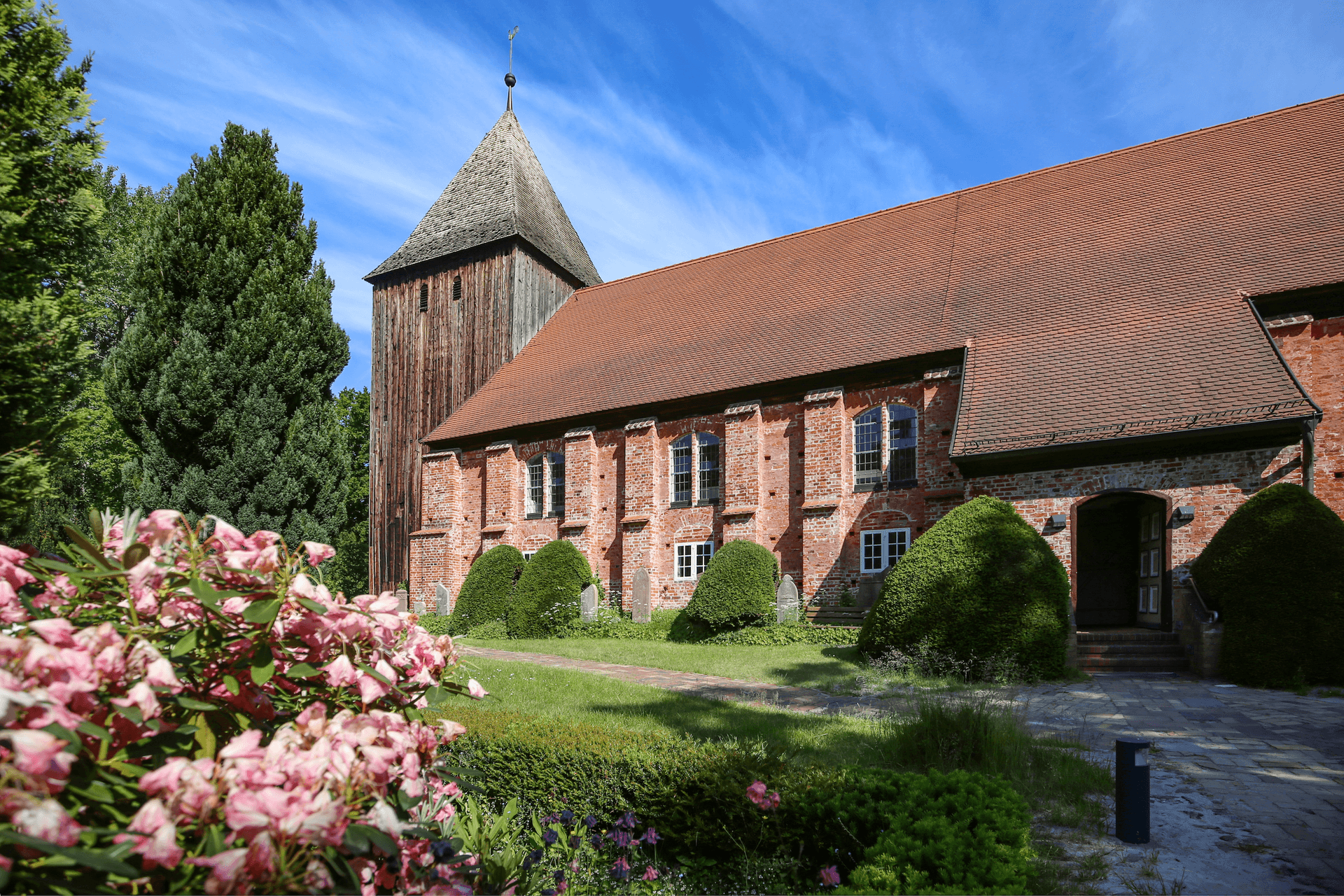 Historische Seemannskirche in Prerow mit Backsteinfassade, Holzturm und blühendem Kirchgarten.
