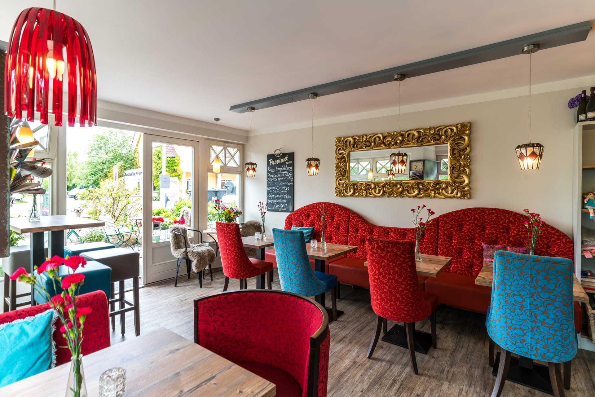 Gemütliches Café mit roten Polstern und goldenen Spiegeln