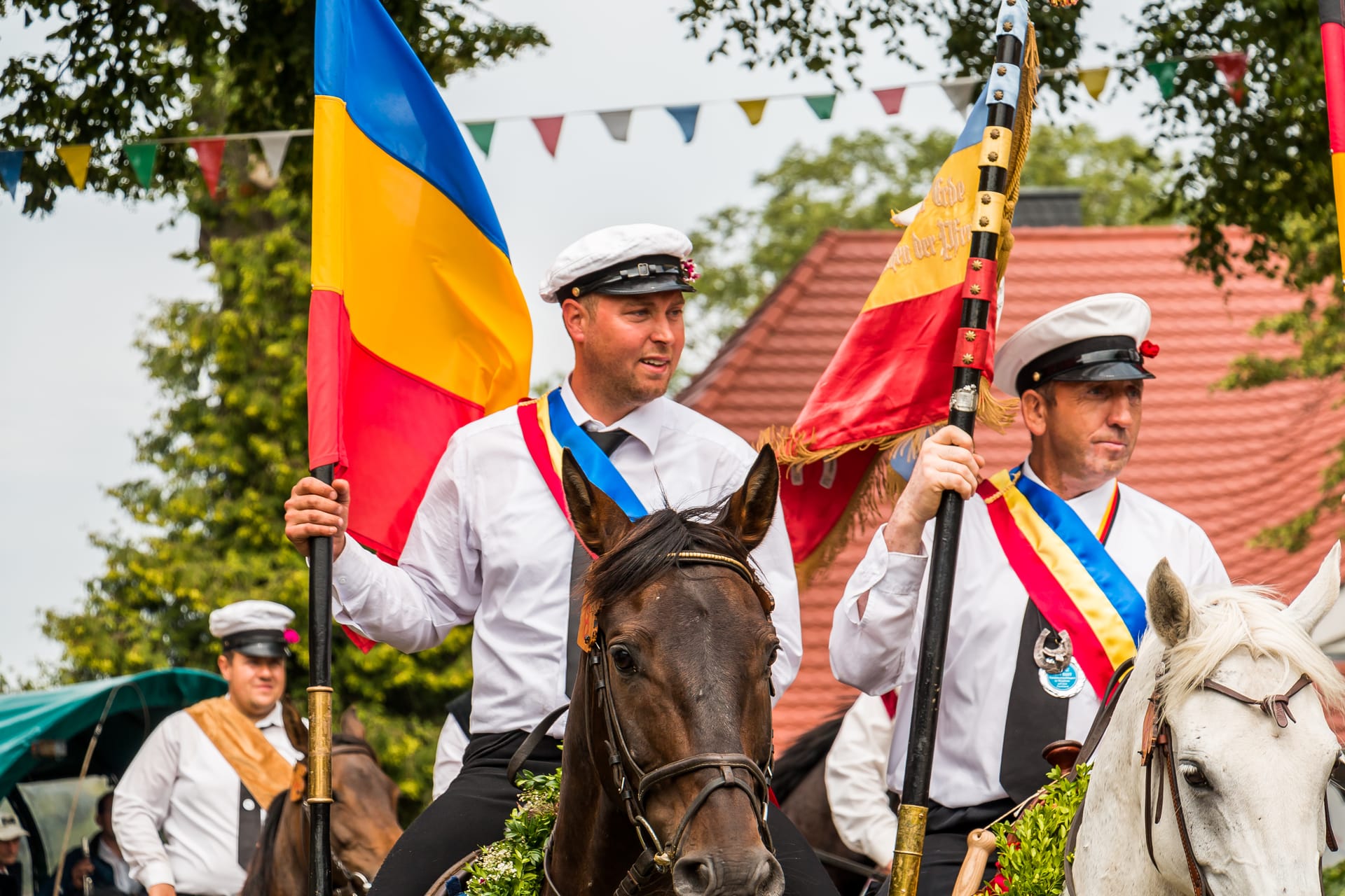 Zwei Reiter vom Tonnenbund sitzen auf Pferden und halten Fahnen