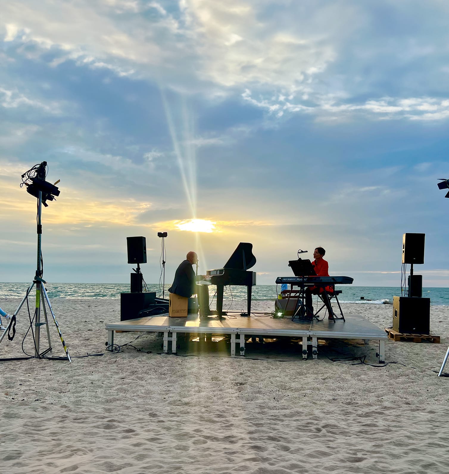 Klavierspieler spielt am Ostseestrand bei Sonnuntergang