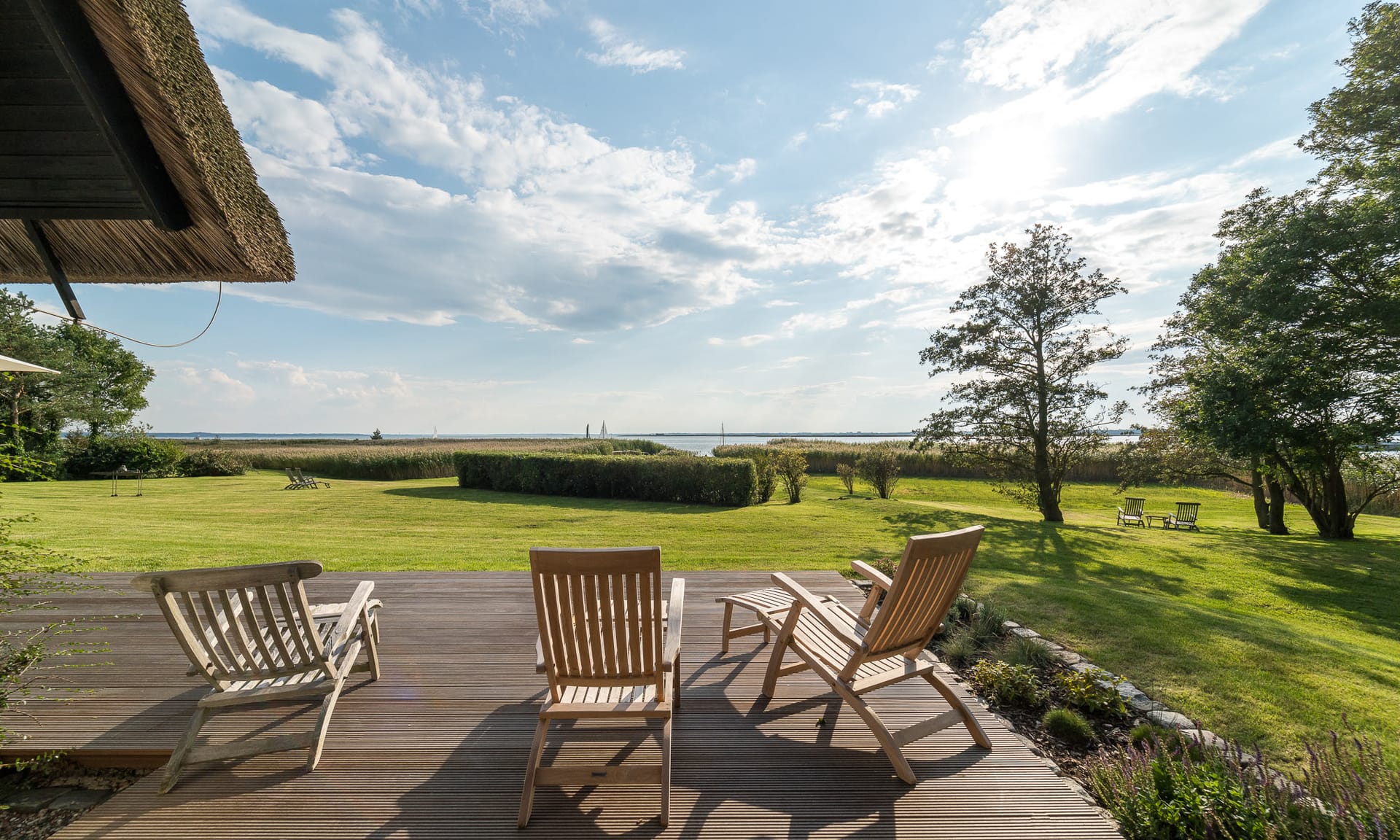 Terrasse mit Boddenblick und Liegestühlen in naturnaher Umgebung