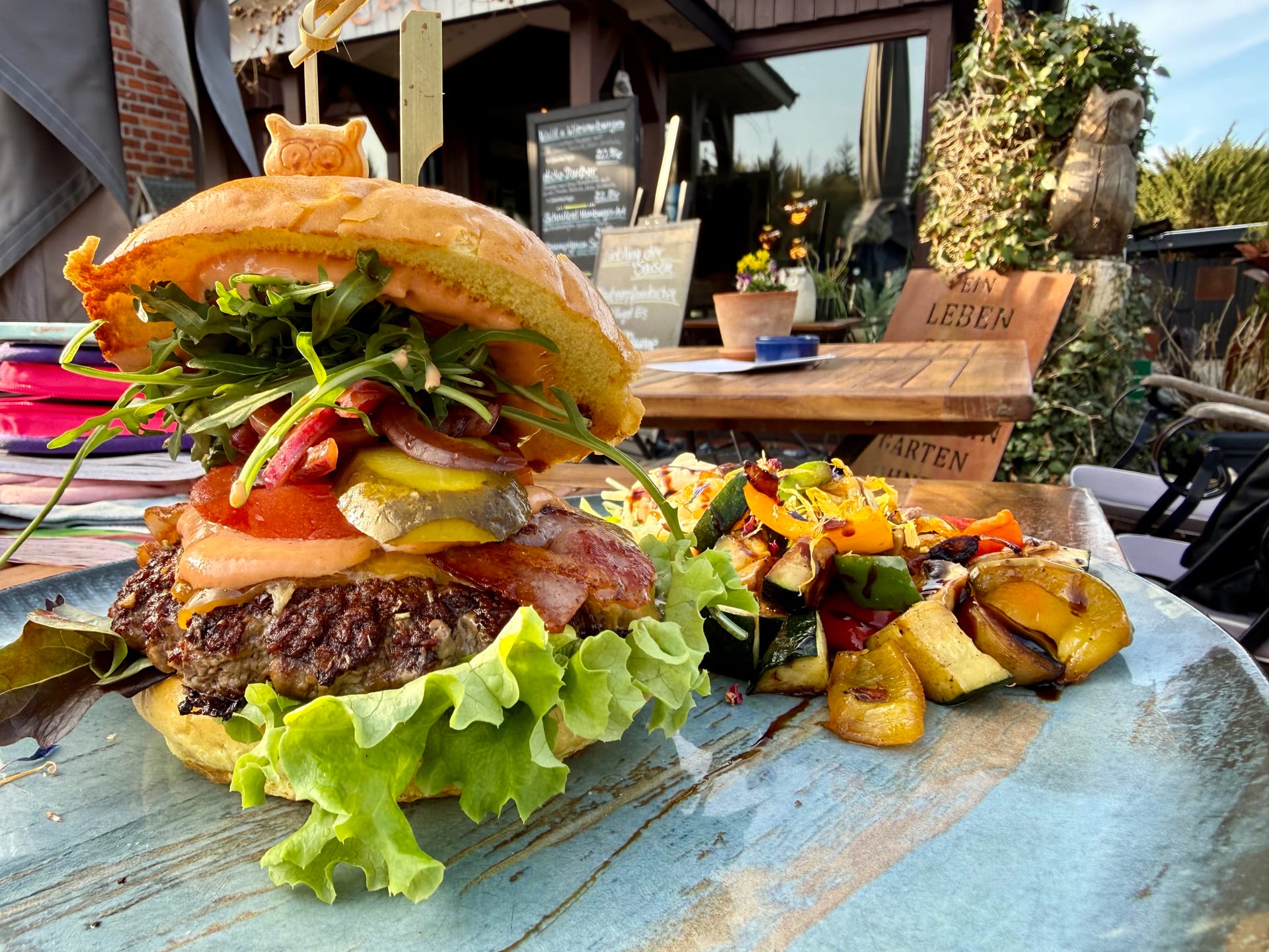 Saftiger Burger mit Gemüsebeilage auf Terrasse serviert