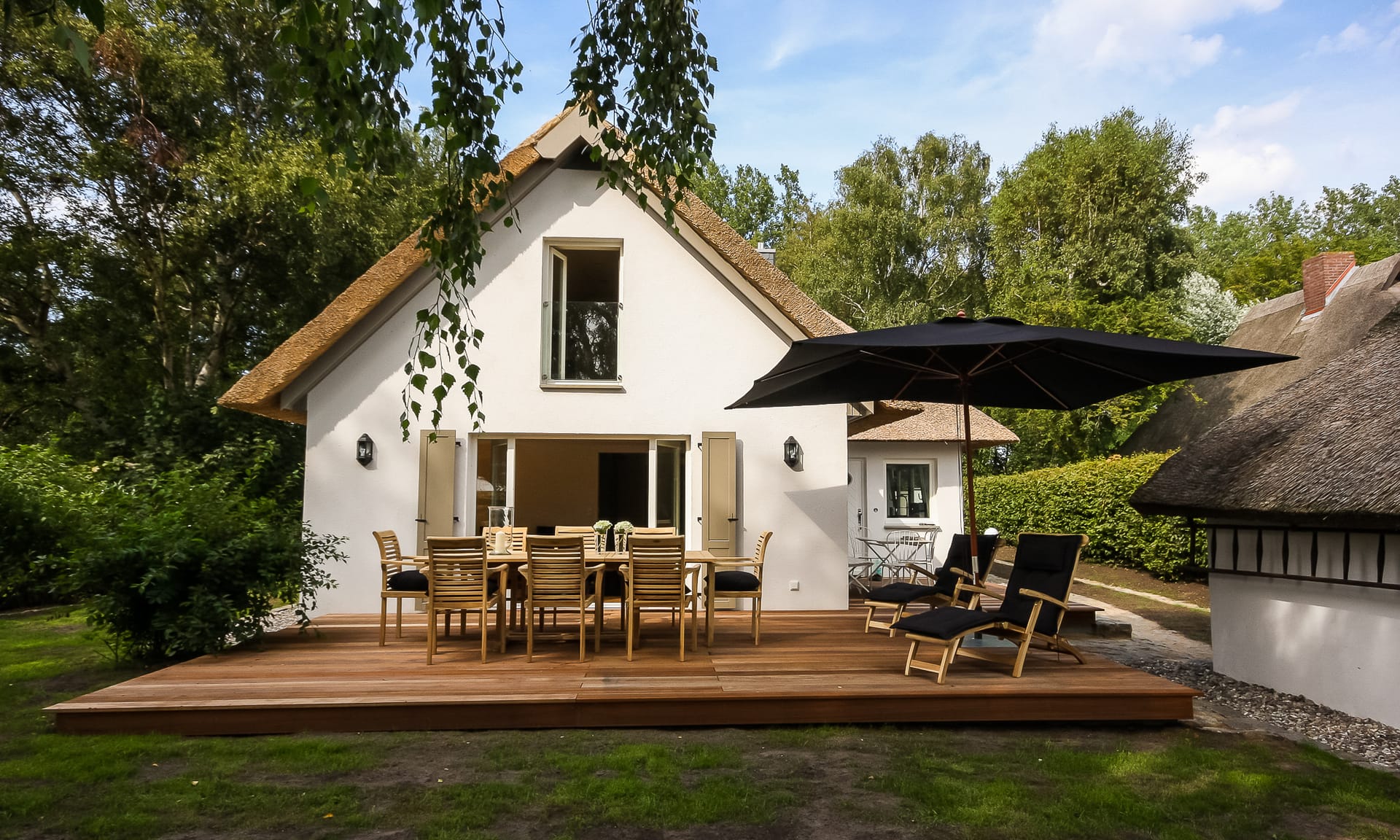 Terrasse mit Esstisch und Liegen am Ferienhaus im Grünen
