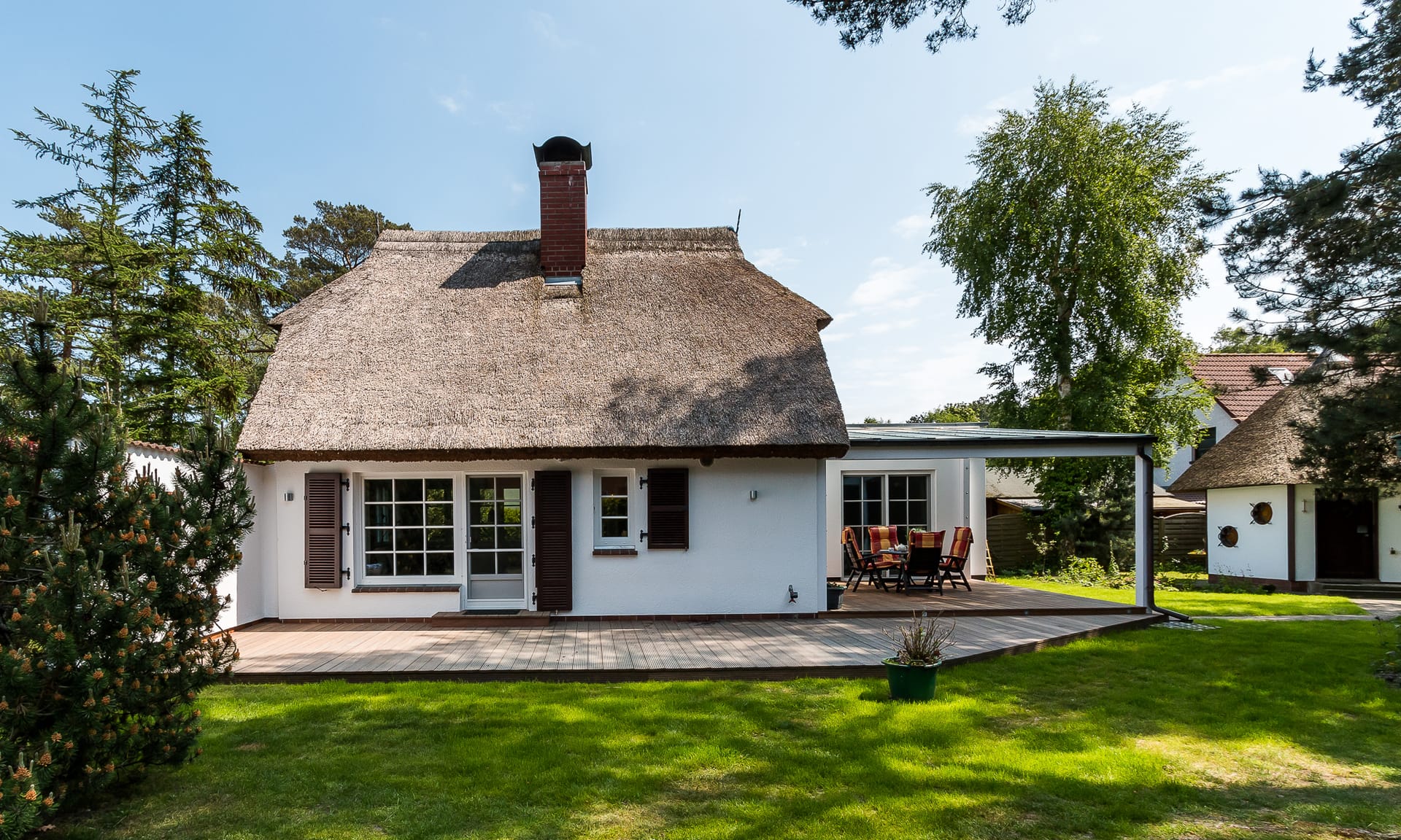Weißes Reetdachhaus mit großer Terrasse und Garten
