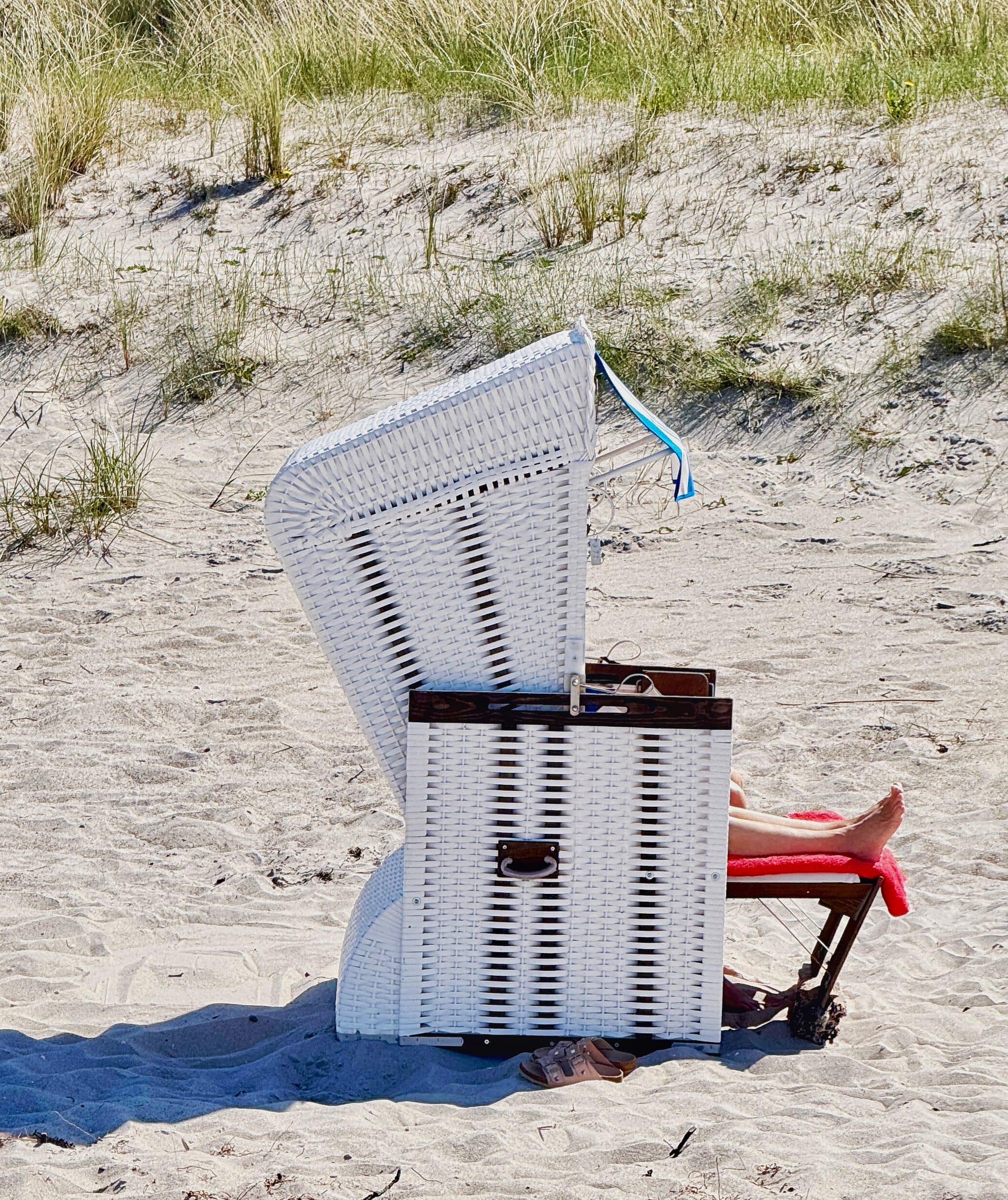 Person sitzt im Strandkorb und Beine gucken raus