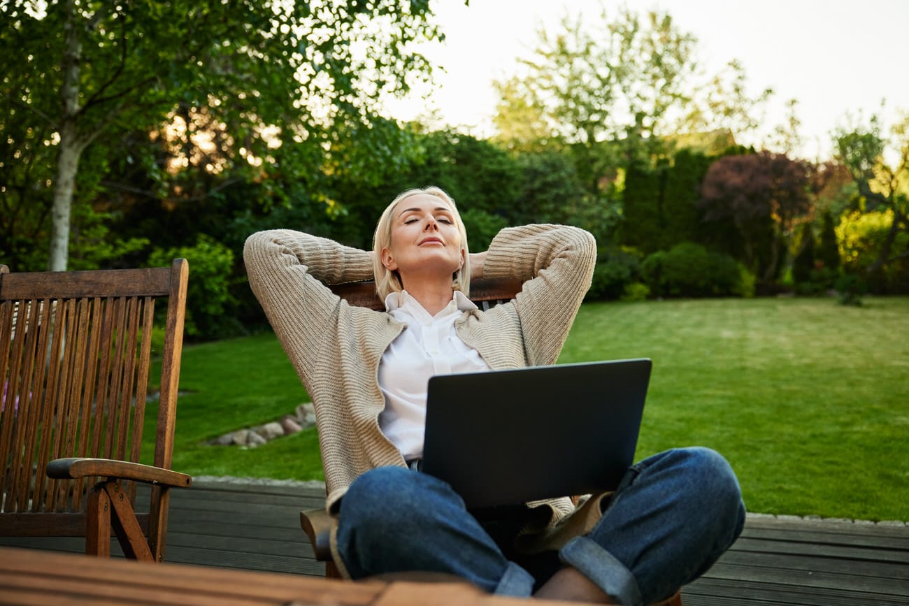 Frau entspannt mit Laptop im grünen Garten